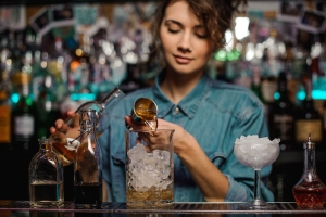 Junge Arbeitnehmerin an der Bar mixt Cocktail
