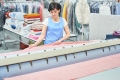 Junge Arbeitnehmerin arbeitet in Wäscherei mit Bügelmaschine