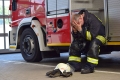 Überforderter Feuerwehrmann birgt sitzend Gesicht in seinen Händen