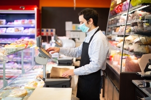 Angestellter im Supermarkt bei der Arbeit mit einer Mund-Nasen-Maske