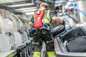 Mann am Flughafen mit Exoskelett hebt Gepäck 