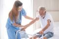 Pflegerin hilft gebrechlichem älteren Patienten
