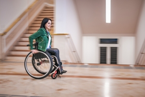 Frau im Rollstuhl fährt einen Gang entlang